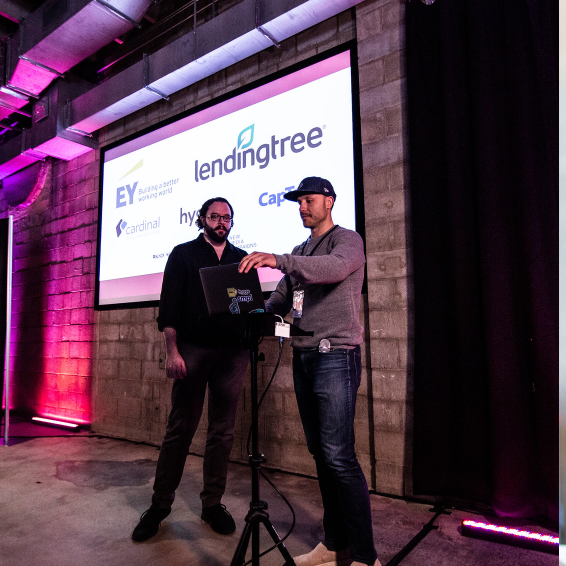 Two organizers on stage with sponsors